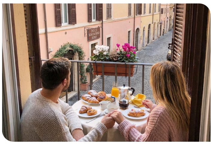 Coppia che fa colazione in camera davanti alla finestra con vista su un vicolo di Roma
